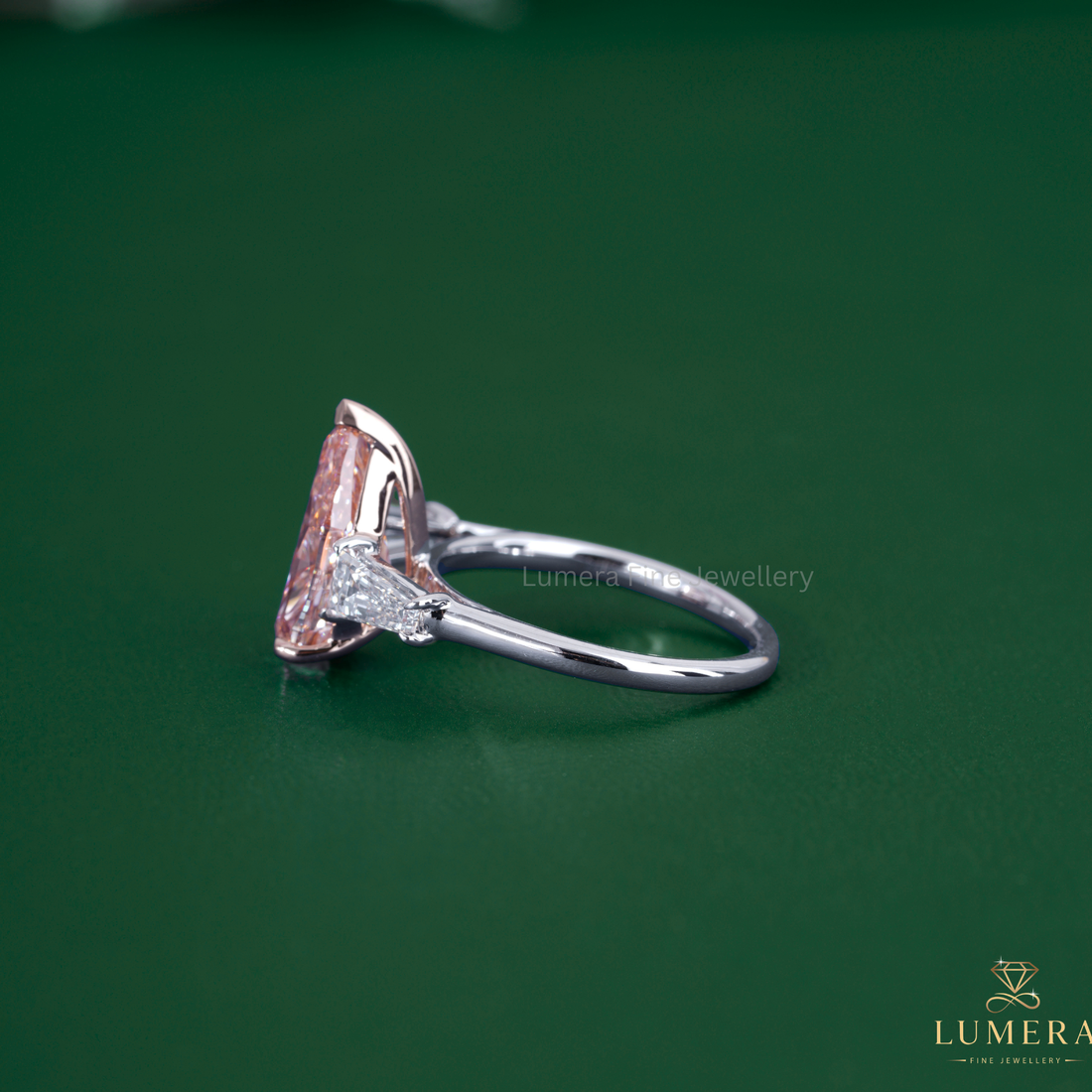 Pear diamond engagement ring set beside a pink stone ring.