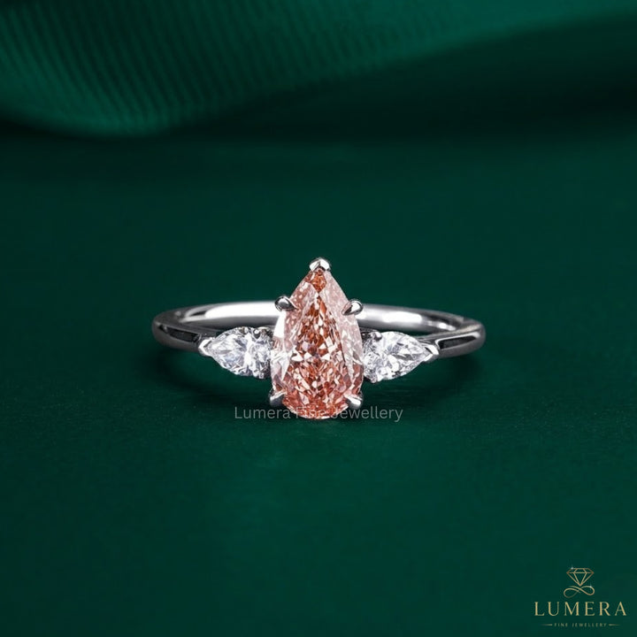 pink stone ring with pear cut three stone ring.
