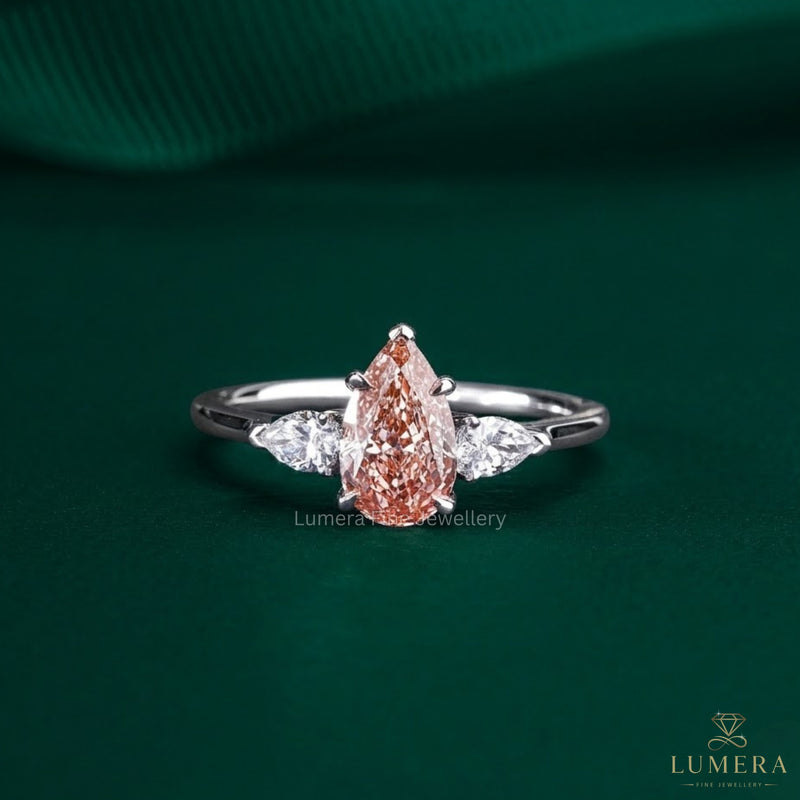 pink stone ring with pear cut three stone ring.
