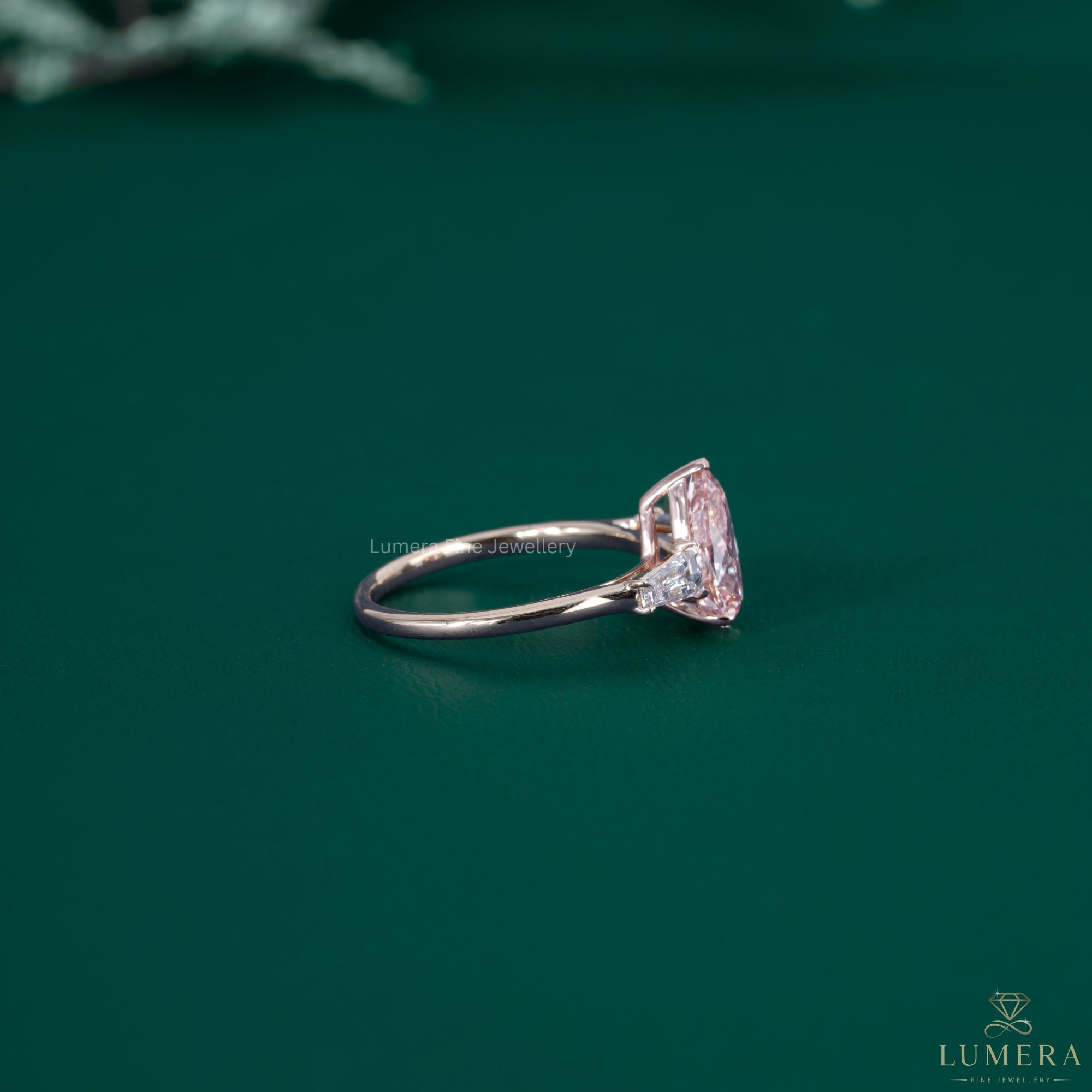 Almond shaped ring beside a pink pear diamond ring.