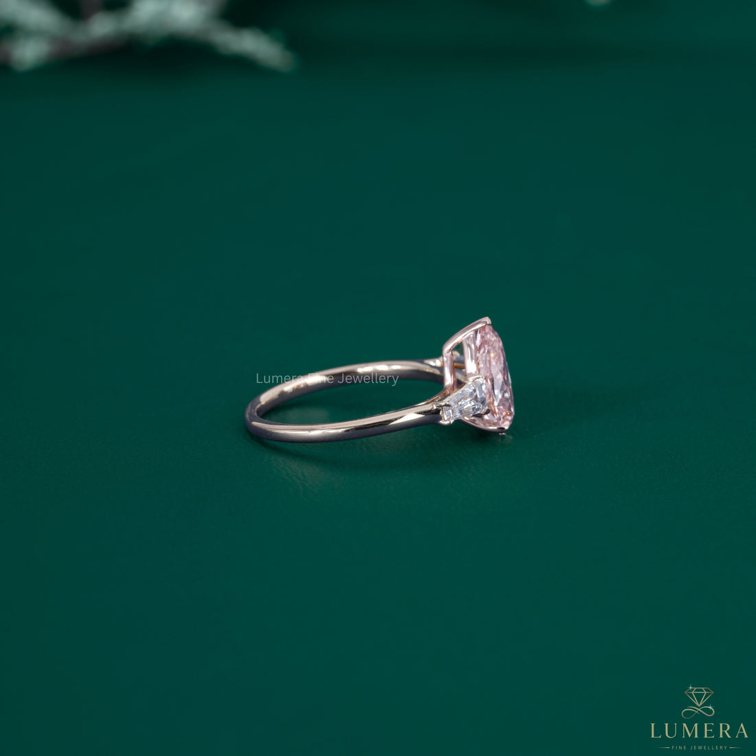 Almond shaped ring beside a pink pear diamond ring.