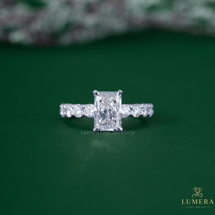Radiant cut diamond engagement ring with pave setting ring.