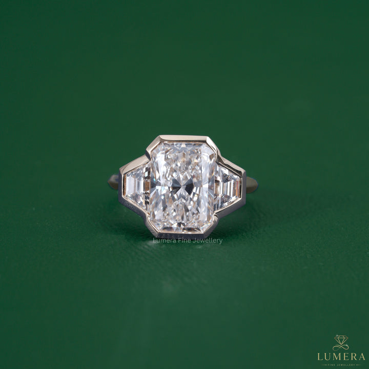 Radiant three stone engagement ring featuring a trapezoid side stone
