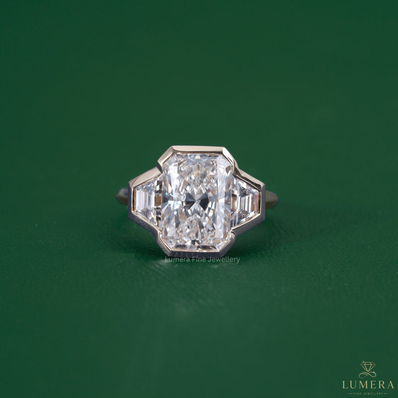 Radiant three stone engagement ring featuring a trapezoid side stone